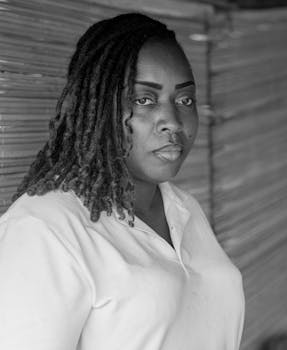 Striking black and white portrait of a serious woman with locs, exuding strength and poise.